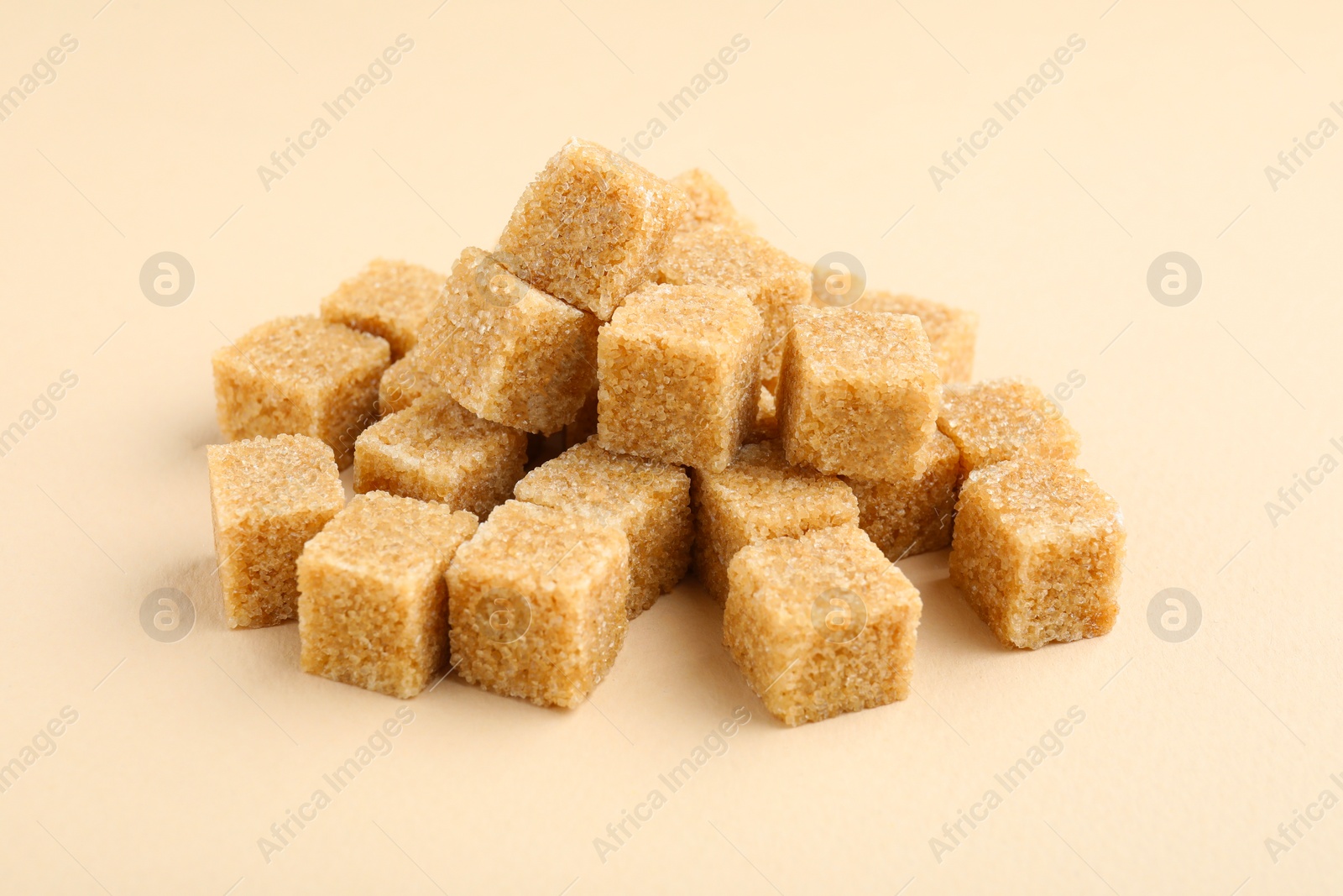 Photo of Brown sugar cubes on beige background, closeup