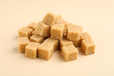 Brown sugar cubes on beige background, closeup