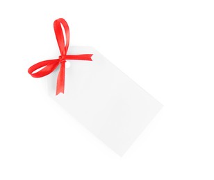 Photo of Blank gift tag with red satin ribbon on white background, top view