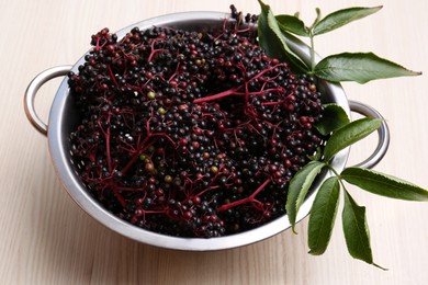 Photo of Many tasty elderberries (Sambucus) on wooden table