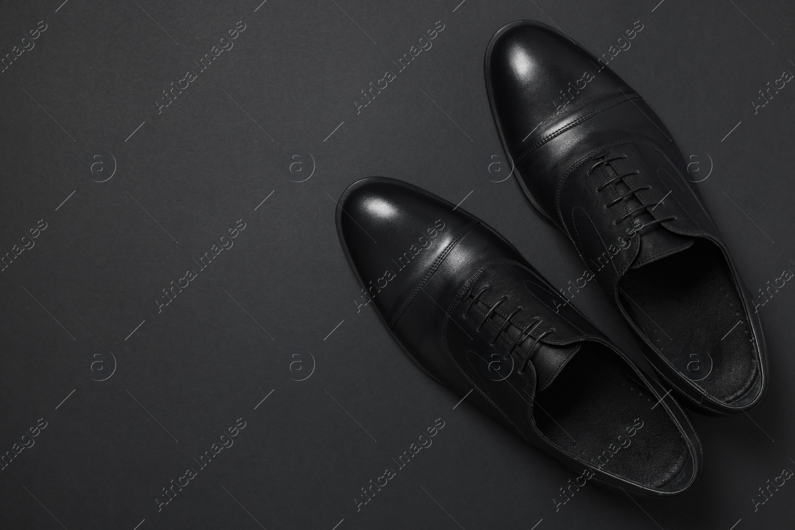 Photo of Pair of leather men shoes on black background, top view. Space for text