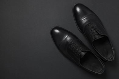 Photo of Pair of leather men shoes on black background, top view. Space for text