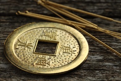 Acupuncture needles and Chinese coin on wooden table, closeup