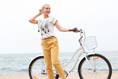 Beautiful woman in casual outfit with bicycle on sea coast