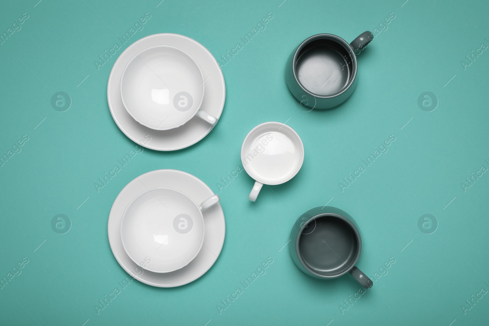 Photo of Different cups on turquoise background, flat lay