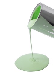 Photo of Pouring light green paint from can on white background, closeup