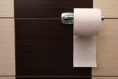 Holder with soft toilet paper roll in bathroom. Space for text