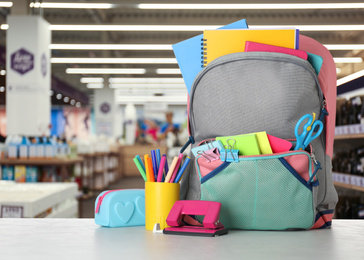 Bright backpack with school stationery on table in shopping mall