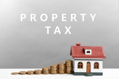 Image of Text Property Tax near stacked coins and house model on grey background