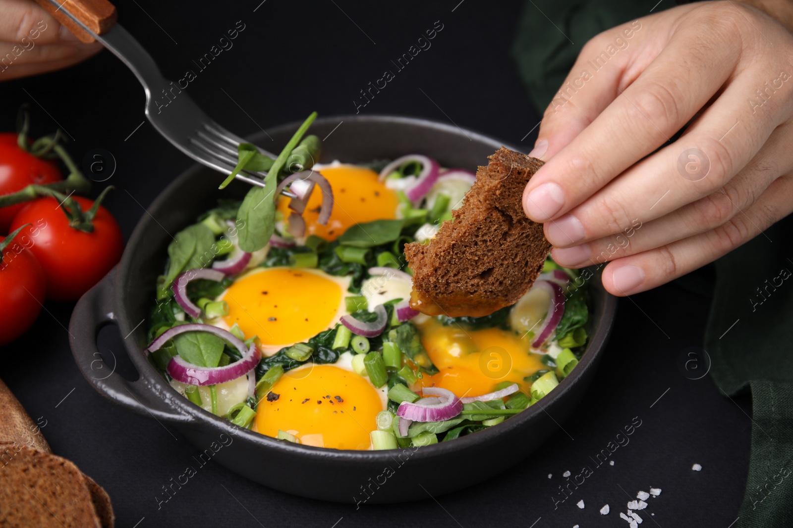 Photo of Woman dipping piece of bread into egg yolk, closeup. Eating tasty Shakshuka