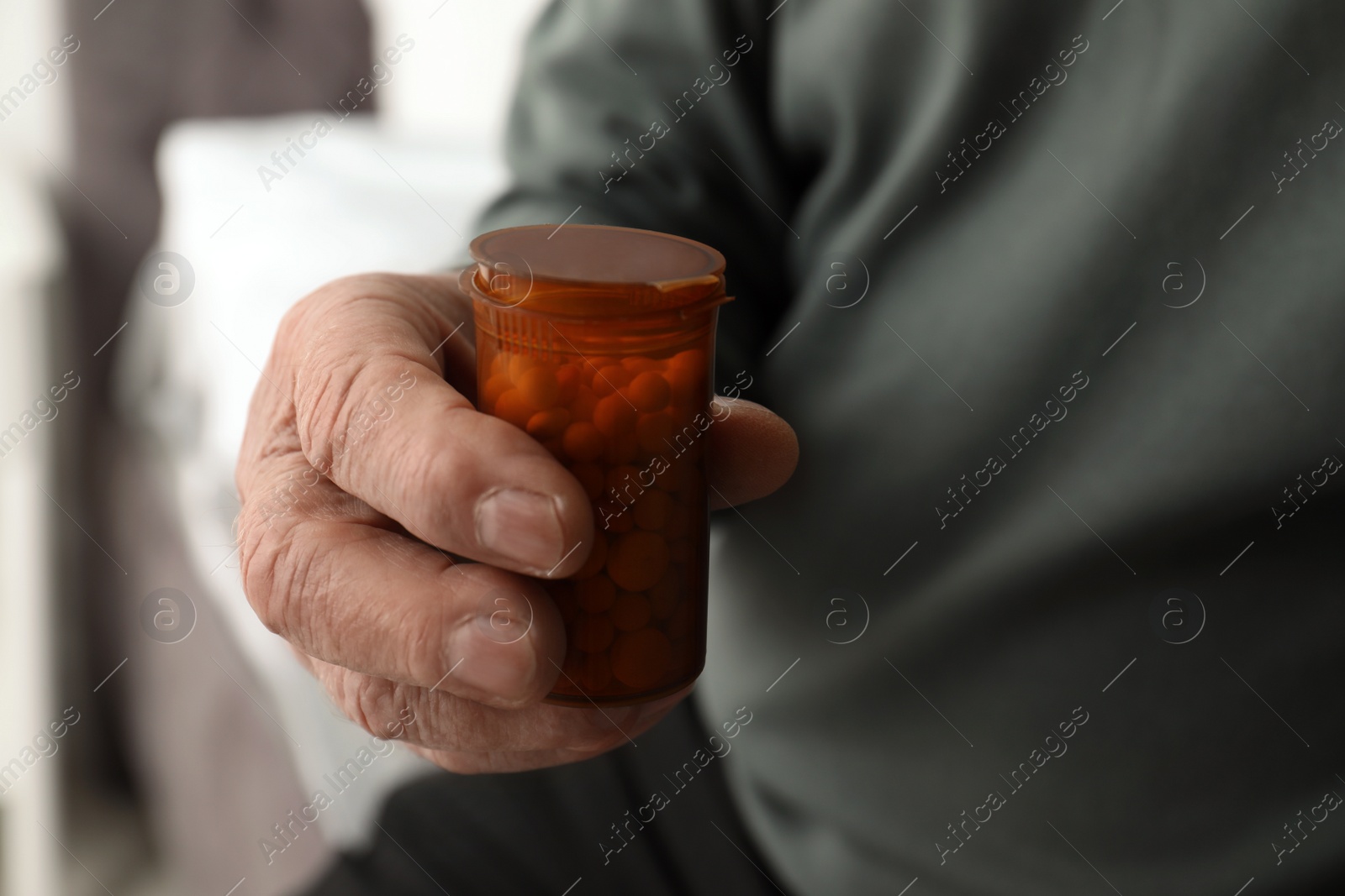 Photo of Senior man holding bottle with pills in his hand, closeup