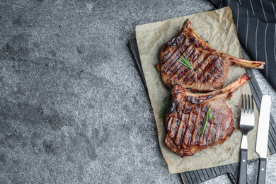 Photo of Delicious beef steaks served on grey table, flat lay. Space for text