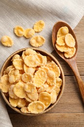 Photo of Bowl and spoon with tasty corn flakes on wooden table, flat lay