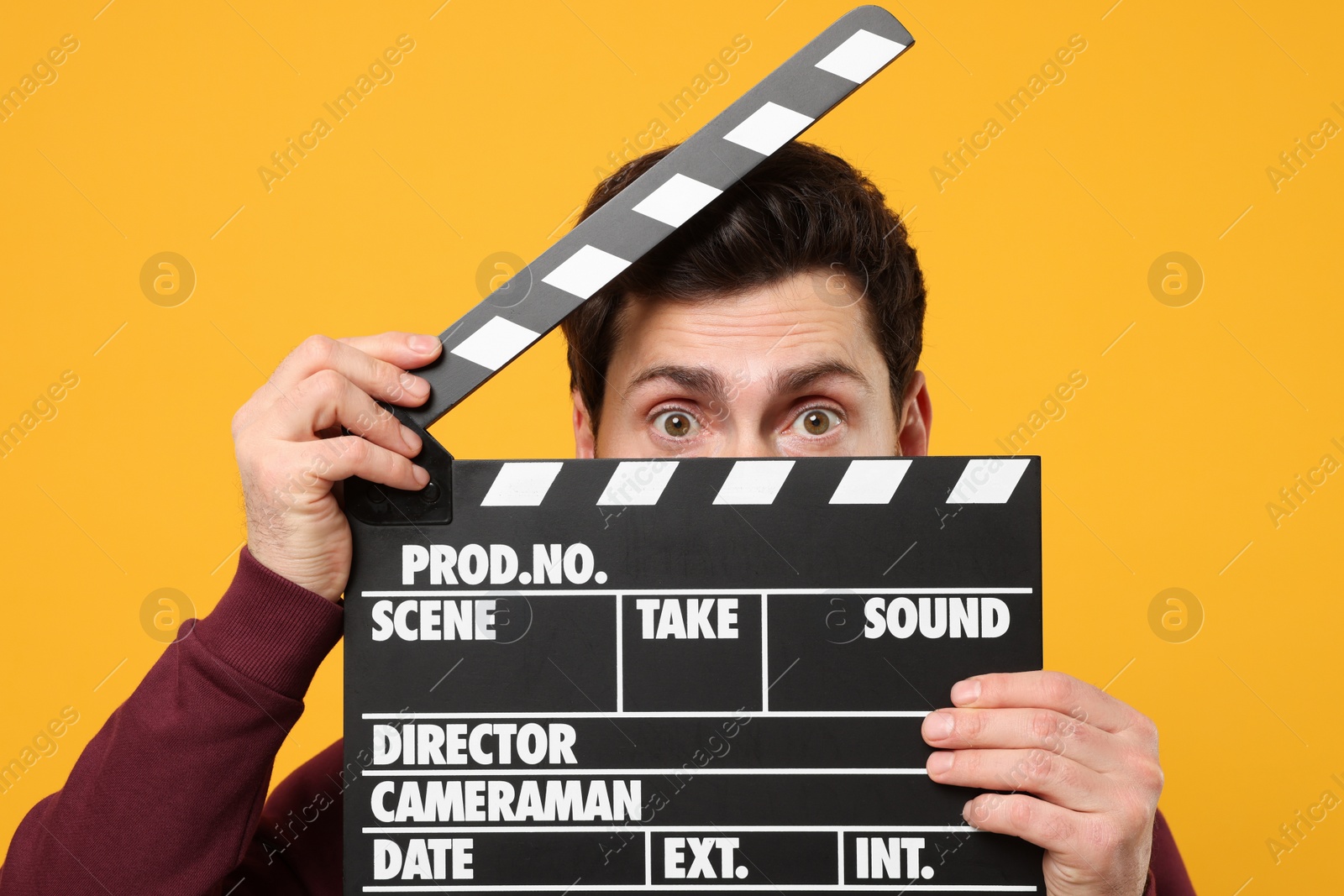 Photo of Surprised actor holding clapperboard on orange background