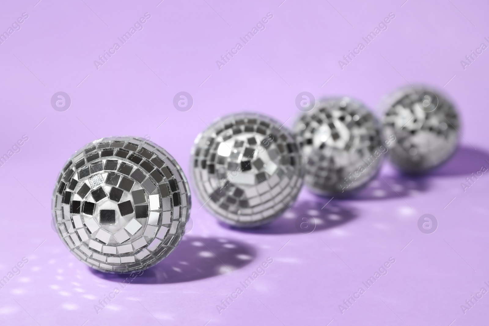 Photo of Row of shiny disco balls on lilac background