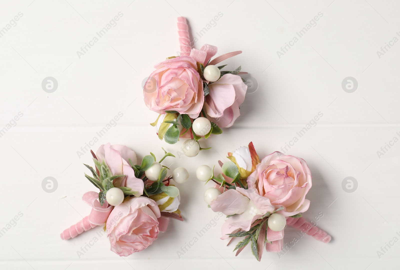 Photo of Beautiful boutonnieres on white background, flat lay