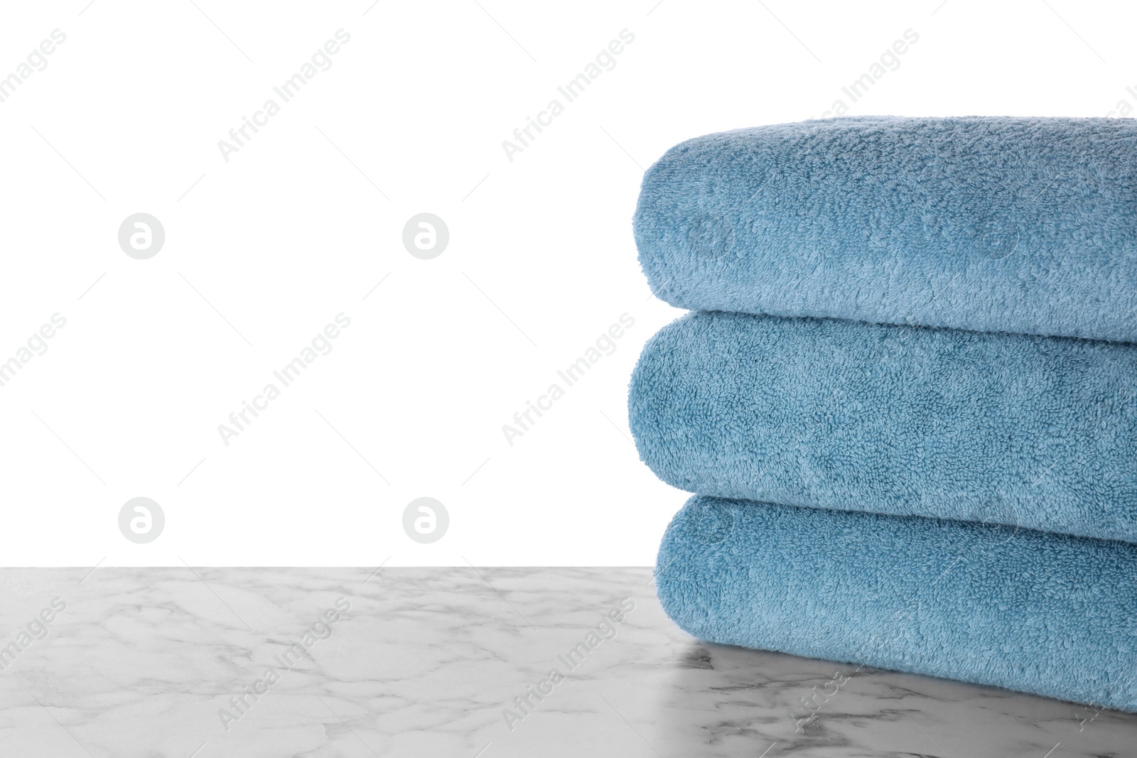 Photo of Fresh towels on marble table against white background. Space for text