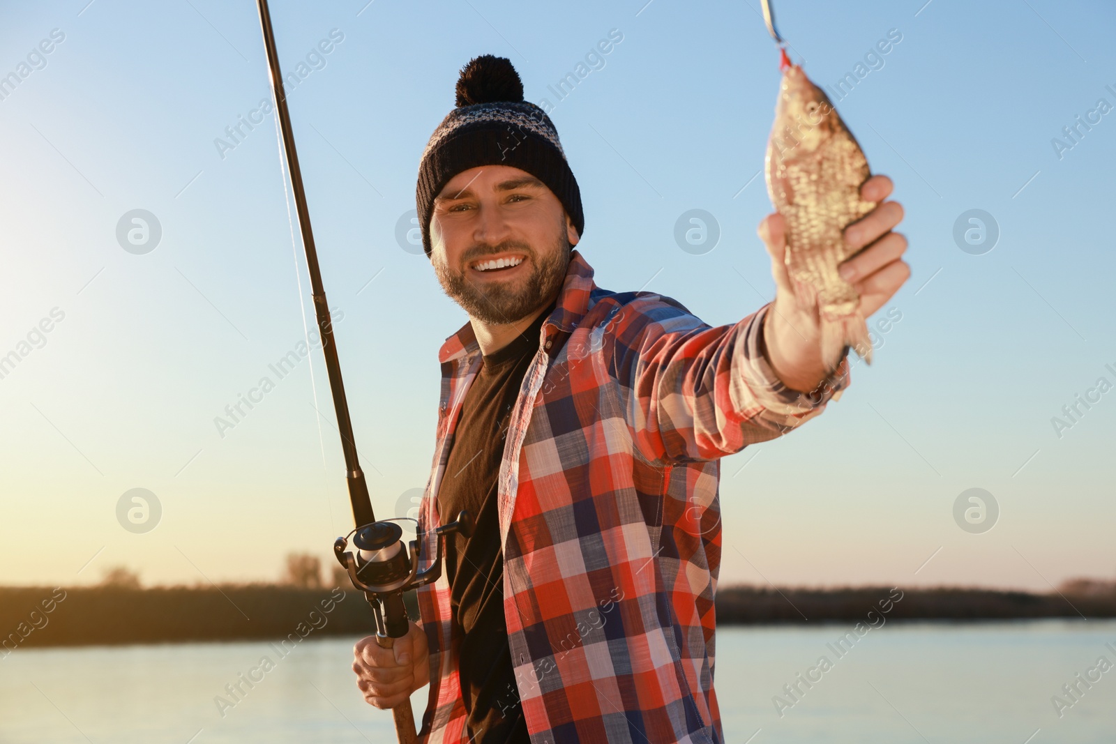 Photo of Fisherman with rod and caught fish at riverside