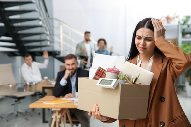 Upset dismissed young woman carrying box with stuff in office, space for text