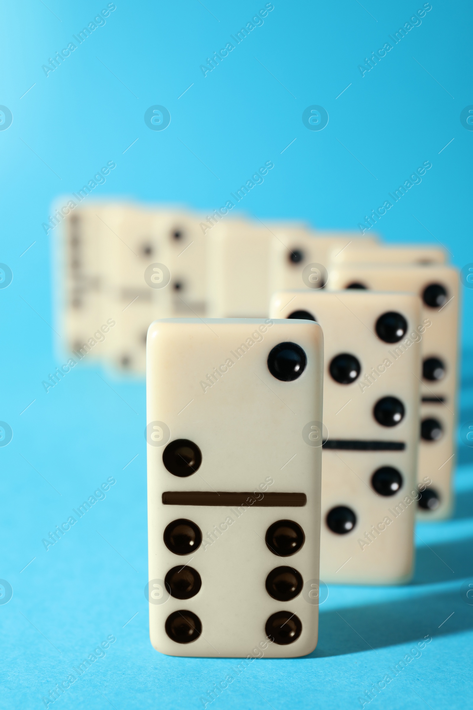 Photo of White domino tiles on turquoise background, closeup. Space for text