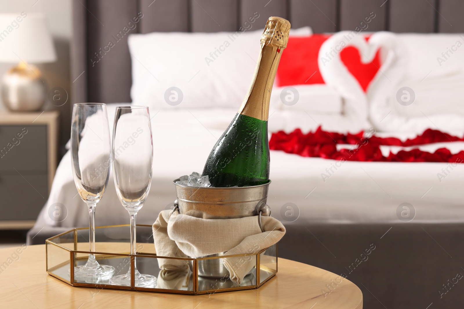 Photo of Honeymoon. Sparkling wine and glasses on wooden table in room