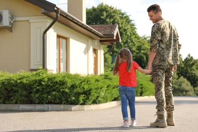Photo of Father in military uniform with his little daughter outdoors