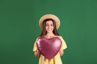 Photo of Portrait of young woman with heart shaped balloon on color background