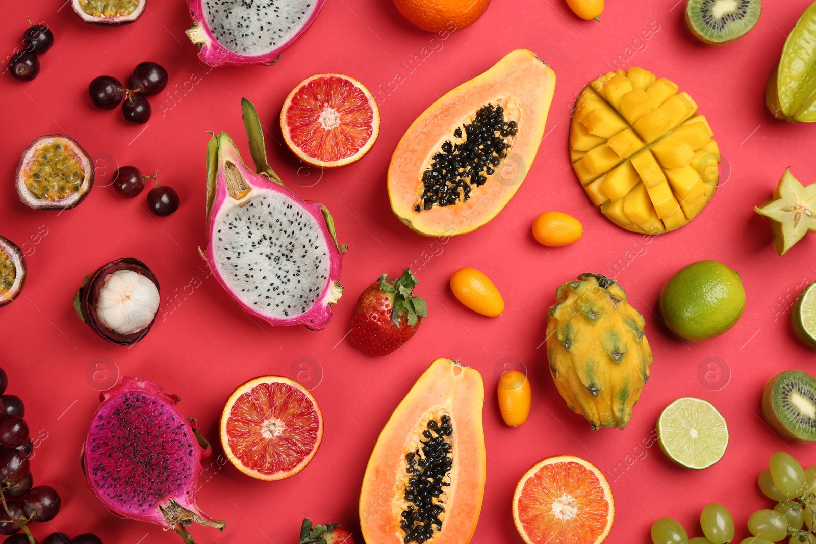 Photo of Many different delicious exotic fruits on red background, flat lay