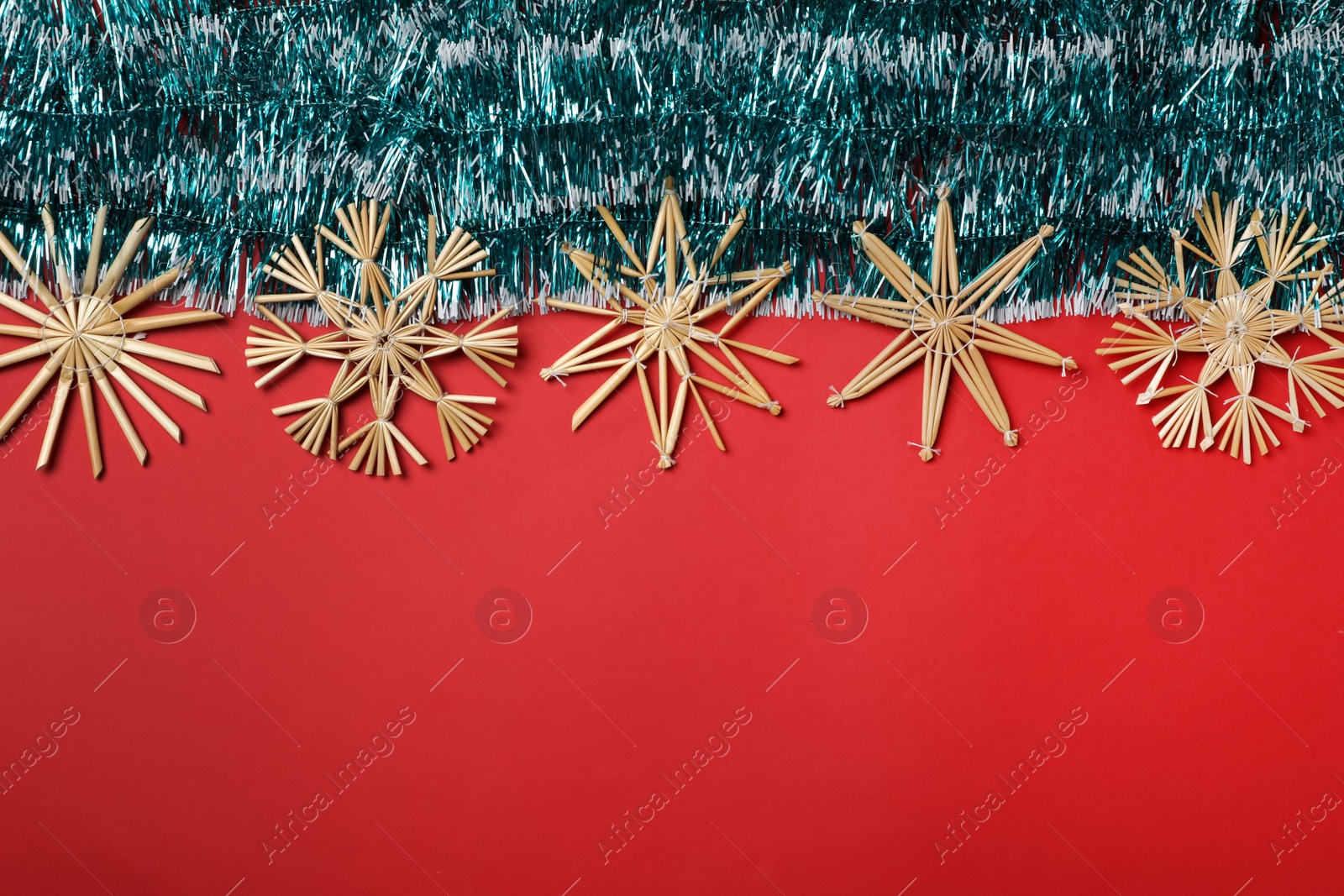 Photo of Bright tinsel and snowflakes on red background, flat lay. Space for text