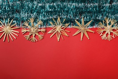 Bright tinsel and snowflakes on red background, flat lay. Space for text