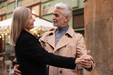 Affectionate senior couple dancing together on city street