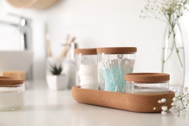 Photo of Glass jars with cotton pads and buds on countertop in bathroom. Space for text