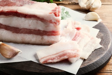 Photo of Tasty salt pork with garlic and parsley on wooden table, closeup