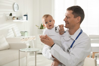 Photo of Pediatrician with cute little baby in clinic. Space for text