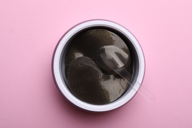 Photo of Package of under eye patches on pink background, top view. Cosmetic product