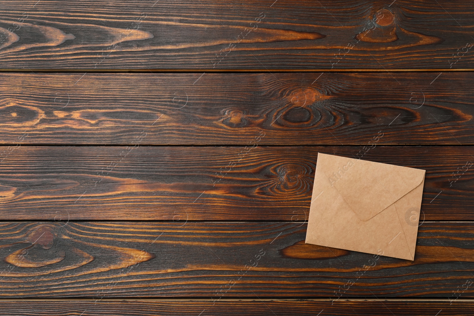 Photo of Kraft paper envelope on wooden background, top view. Space for text