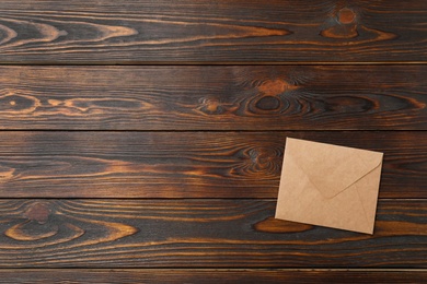 Kraft paper envelope on wooden background, top view. Space for text