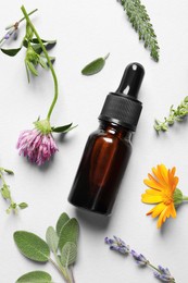 Bottle of essential oil, different herbs and flowers on white background, flat lay