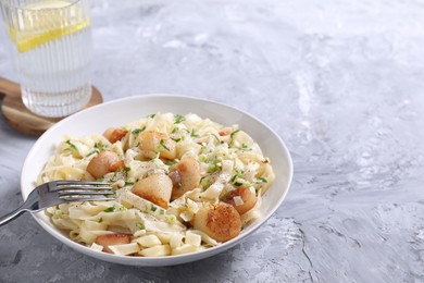 Photo of Delicious scallop pasta with spices served on gray textured table, closeup. Space for text