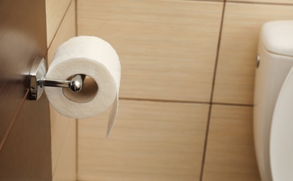 Photo of Holder with soft toilet paper roll in bathroom. Space for text