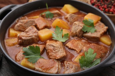Photo of Delicious goulash in pot on wooden table, closeup