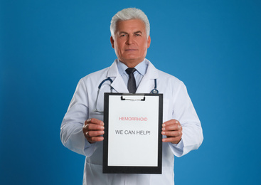 Photo of Doctor holding clipboard with words HEMORRHOID WE CAN HELP on blue background