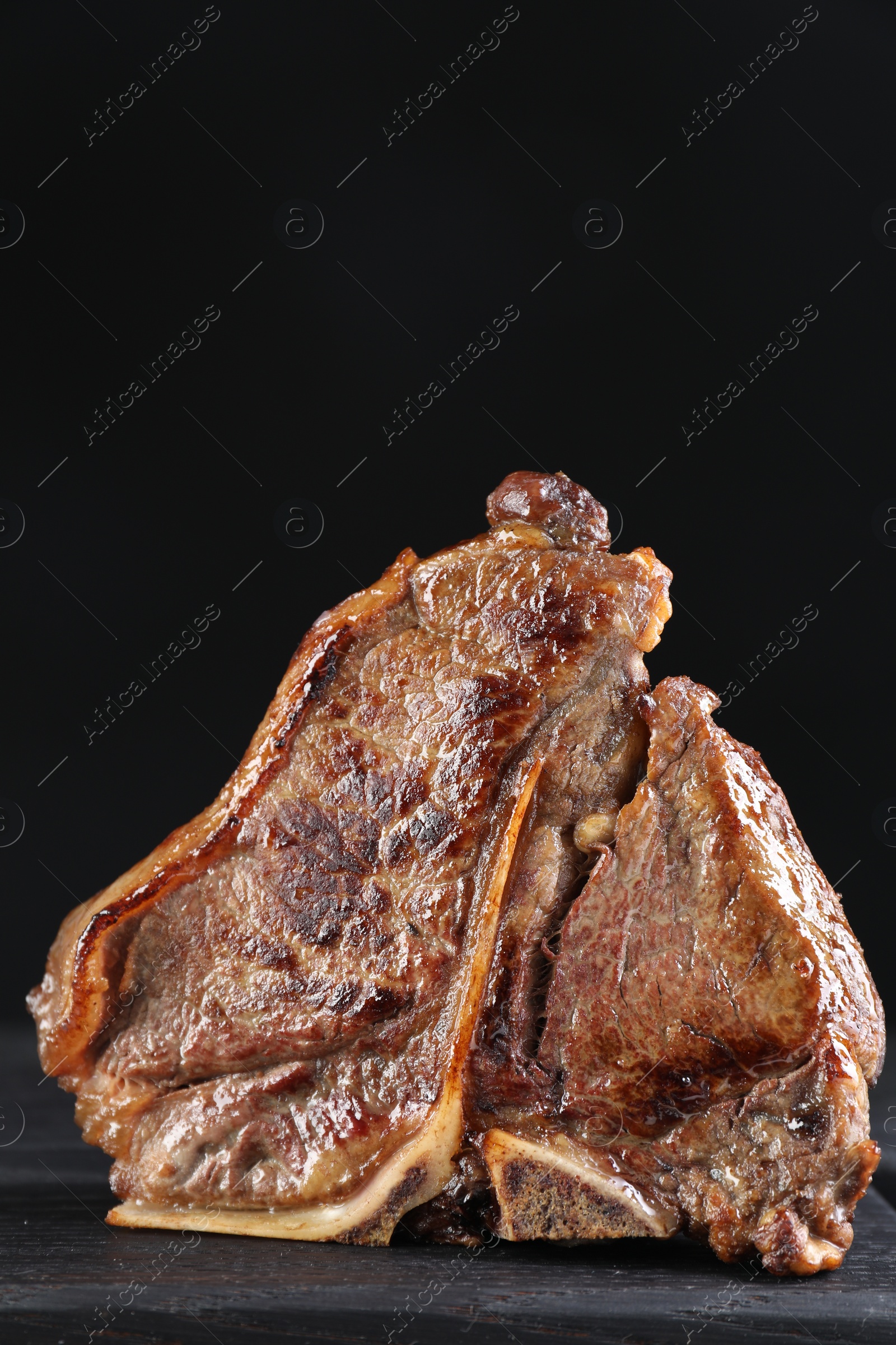 Photo of Delicious fried beef meat on table against black background