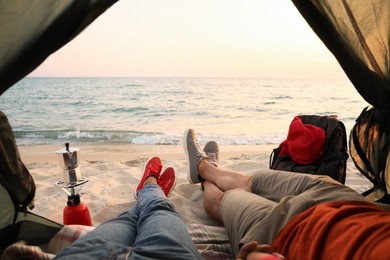 Photo of Couple resting in camping tent near sea, closeup