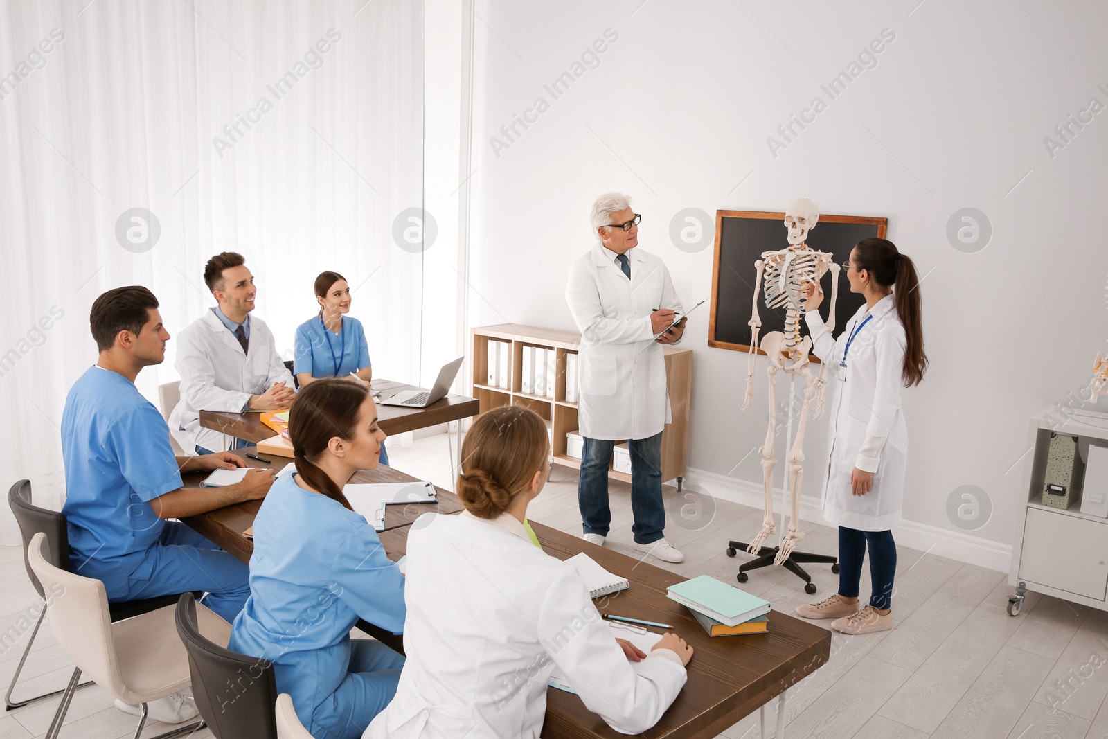 Photo of Medical students and professor studying human skeleton anatomy in classroom