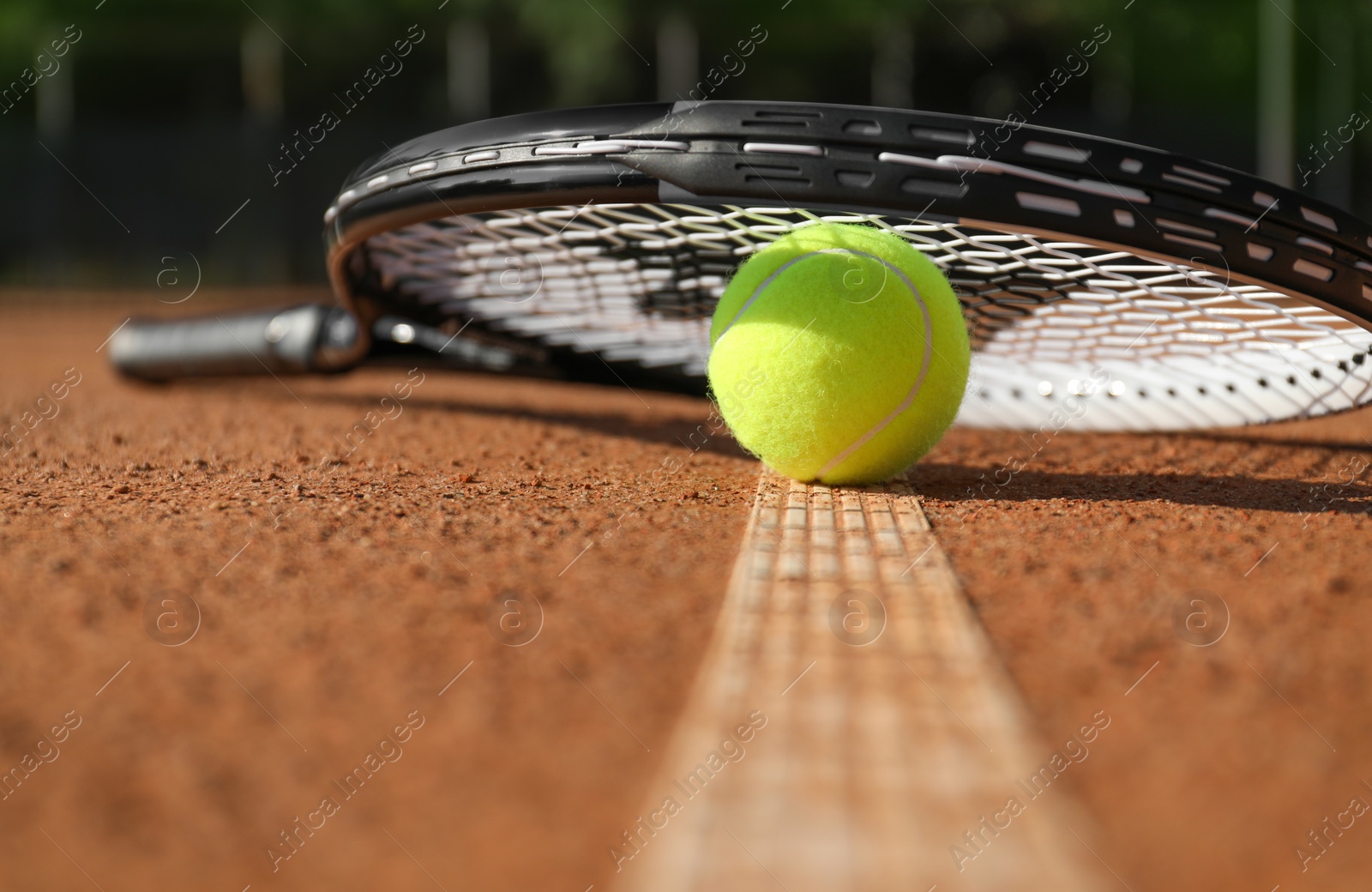 Photo of Tennis ball and racket on clay court, closeup