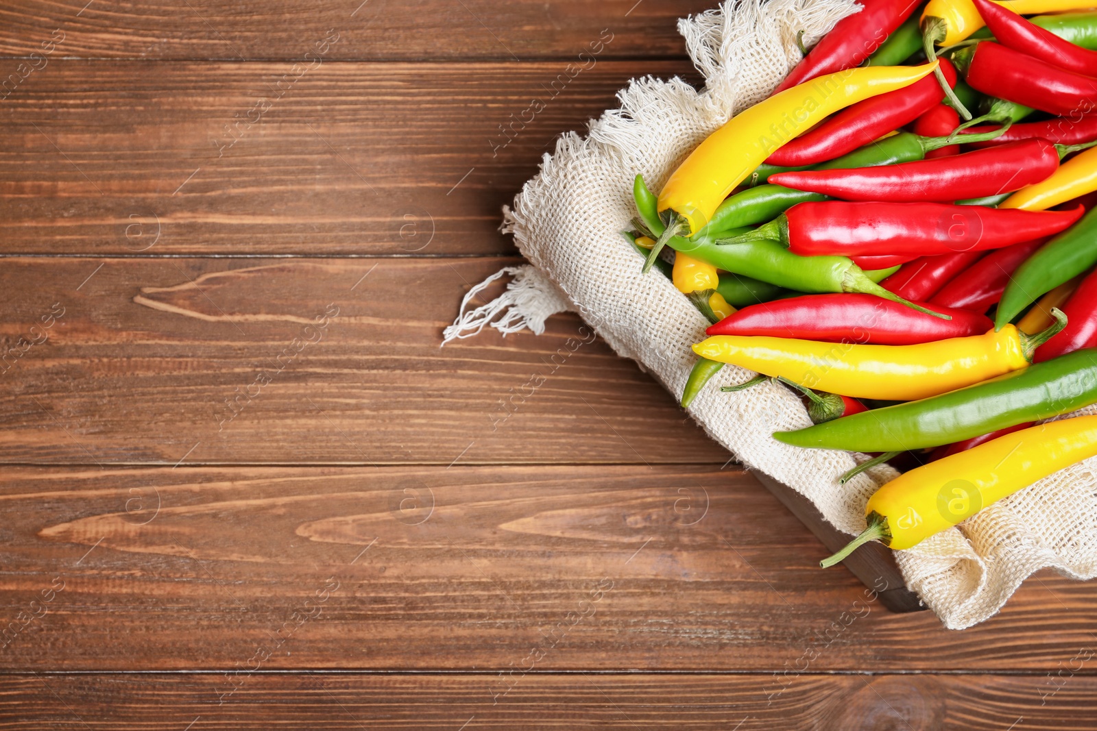 Photo of Crate with chili peppers on wooden background