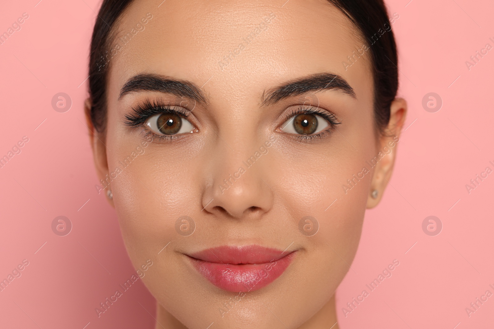 Photo of Beautiful young woman showing extended and ordinary eyelashes on pink background, closeup