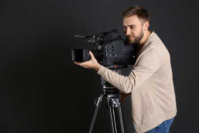 Operator with professional video camera on black background