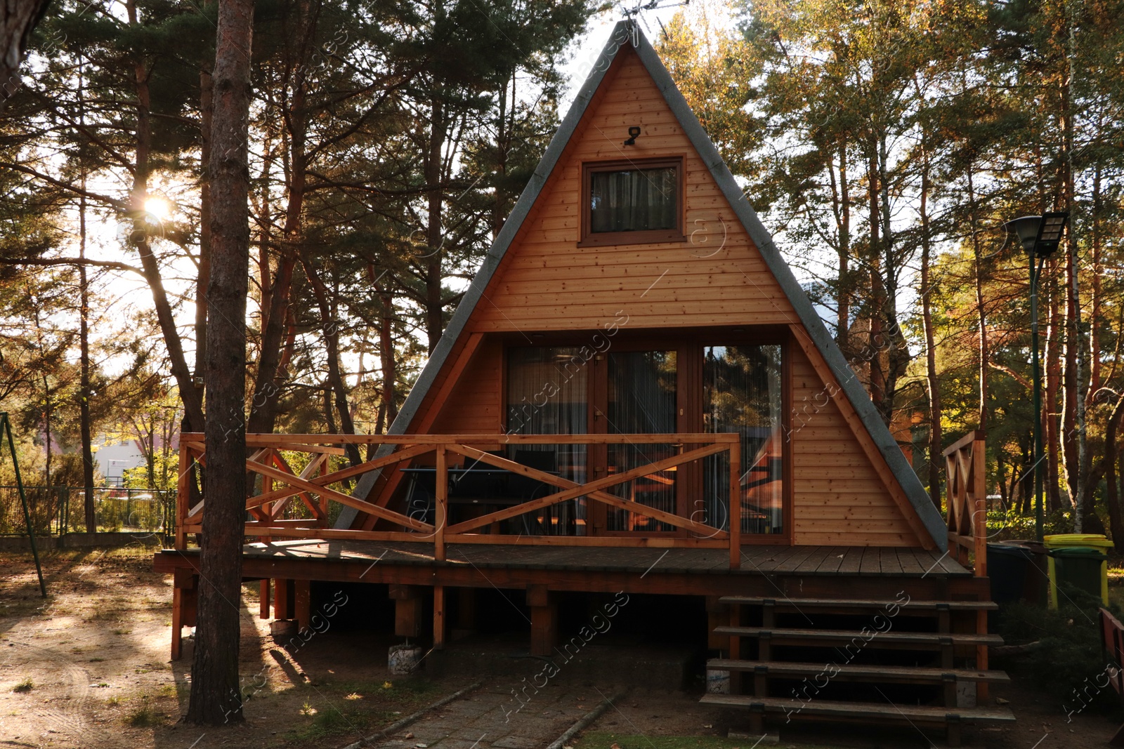 Photo of Picturesque view of modern wooden house with veranda near forest on sunny day